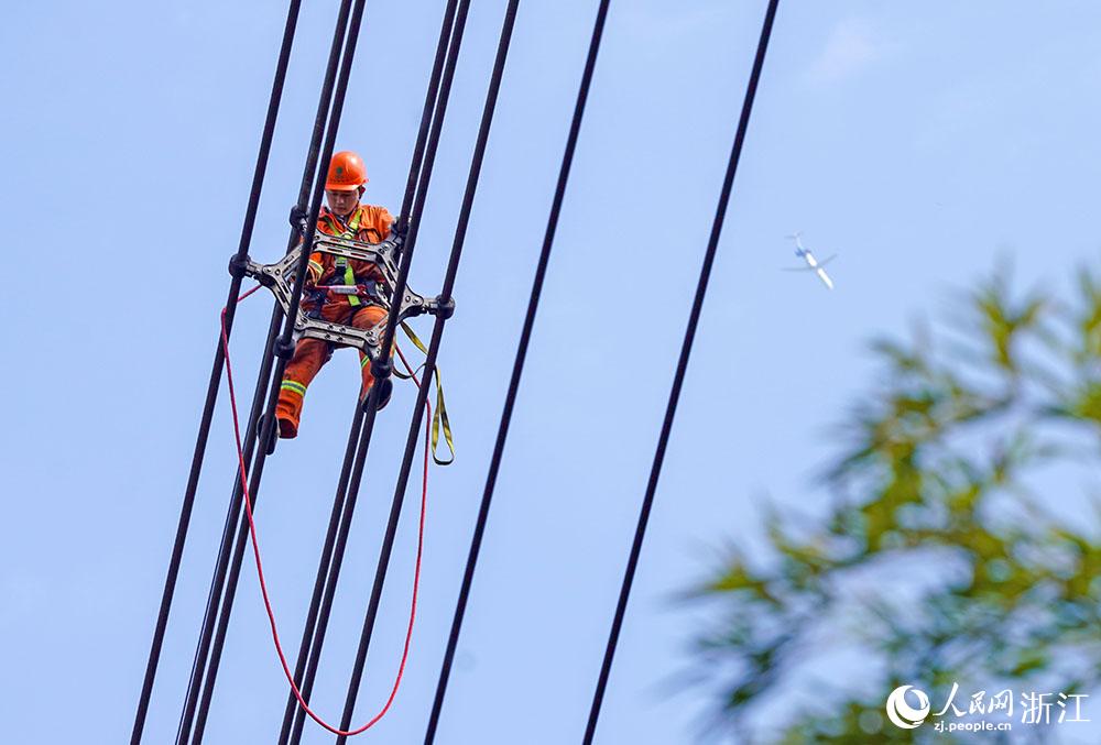3月11日，在浙江省諸暨市河上鎮(zhèn)，浙江省送變電工程有限公司檢修人員在高空的導(dǎo)線上進(jìn)行線路檢修維護(hù)。人民網(wǎng) 章勇濤攝