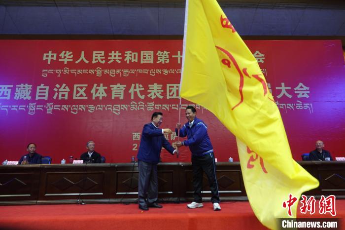 西藏自治區(qū)副主席甲熱·洛桑丹增授代表團團旗，西藏自治區(qū)體育局局長尼瑪次仁接旗?！∪轿木?攝