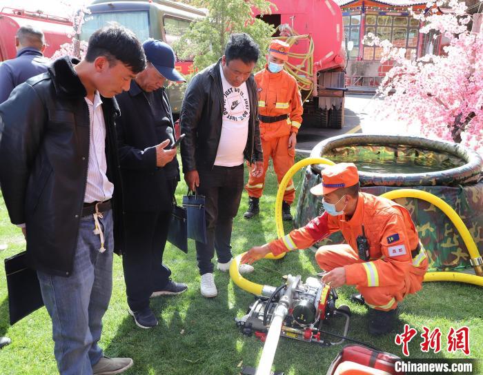 圖為森林消防員為護(hù)林員講解滅火裝備的使用方法?！〔际猩窒乐ш?duì) 供圖