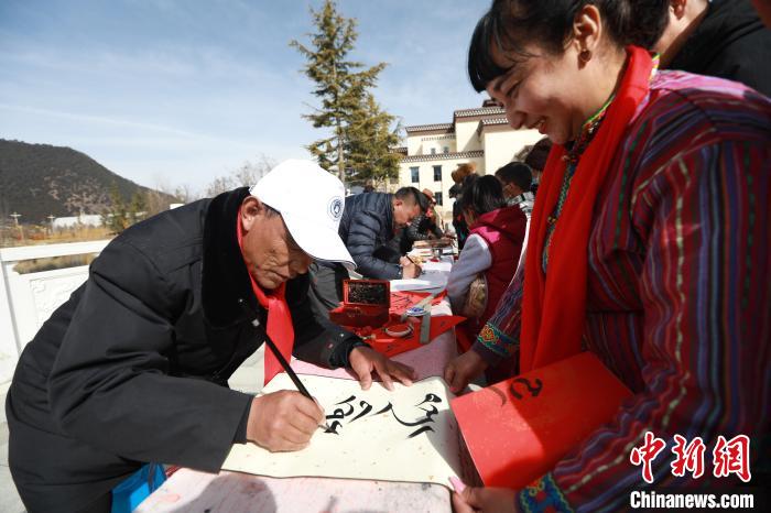 圖為林芝市文聯(lián)書法家協(xié)會(huì)會(huì)員向民眾贈(zèng)送藏文書法作品?！埩?攝